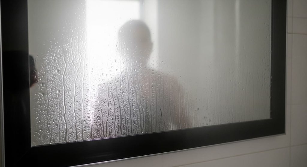fogged up bathroom mirror after hot shower with condensation and water droplets

